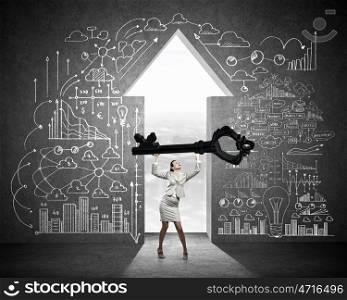 Key to success. Young businesswoman and lifting big key above head