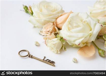 Key with the blooming rose and fresh petals as a symbol of love. Red roses with key