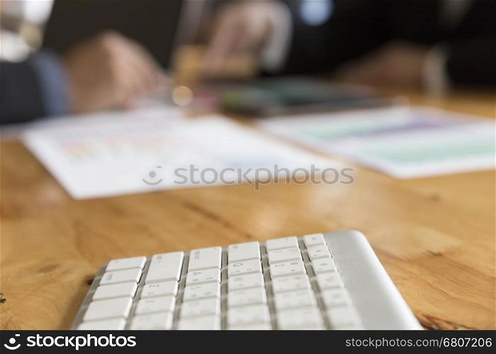 keyboard computer with background of businessman meeting, analyzing and discussing with computer and paperwork document