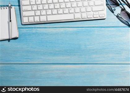 keyboard on table. white modern keyboard with notepad on blue wooden table