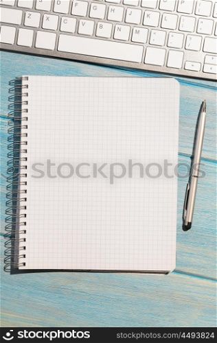 keyboard on table. white modern keyboard with notepad on blue wooden table