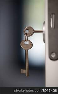 Keys in the door lock. Close-up shot of keys in the lock of open door. One key is in lock another hanging on the ring