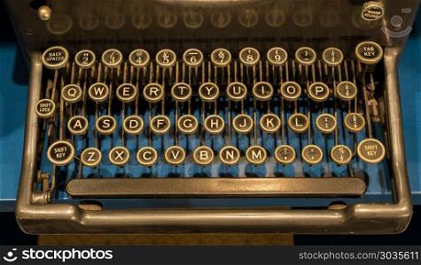 Keys of old mechanical typewriter. Qwerty keys on ancient mechanical typewriter on blue desk surface. Keys of old mechanical typewriter