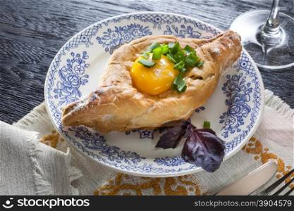 Khachapuri on plate with herbs. Top view. Khachapuri on plate with herbs