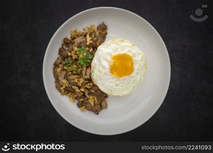 Khao Moo Tod Kratiam Kai Dao, Thai food, streamed rice topped with fried pork with garlic and fried egg in ceramic plate on dark grey texture background