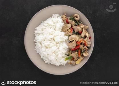 Khao Pad Ka Prao Kruang Nai Gai, Thai food, streamed rice with basil stir fried chicken offal, variety meats, pluck or organ meats on dark tone background, top view