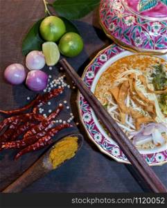 Khao Soi Thai Noodle Curry Soup with chicken on wood table, Khao soi a famous northern Thai food, top view. Traditional Thai Food