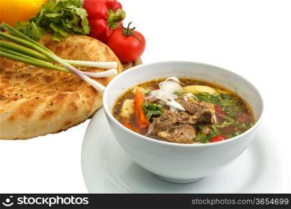 Kharcho soup with bread and vegetables on a white background