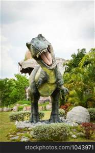 Khon Kaen , Thailand 13 May 2018 : Dinosaur park / different species dinosaur Tyrannosaurus statue T rex in the palm tree garden