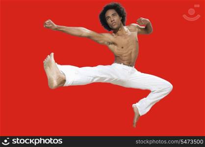 Kickboxer jumping over red background