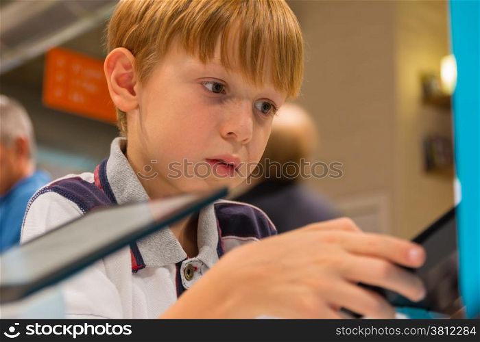 Kid (7-8 years) working with Digital Tablet in a shop