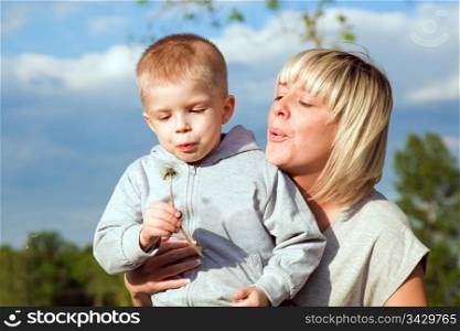 Kid and mother blowing dandelion. Spring time