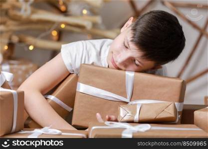 kid boy is sleeping on a lots of gift boxes by the decorated christmas tree. happy winter holiday vacation. kid boy is sleeping on a lots of gift boxes by the decorated christmas tree. happy winter holiday vacation.