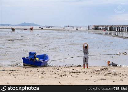 Kid boy playing on the beach with small fishing boat