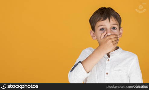 kid covering his mouth with copy space