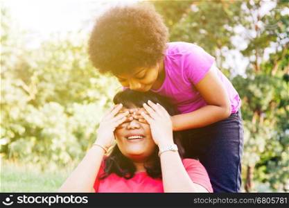 Kid covering mother's eyes in the green park with copy space - Daughter and mother relationship