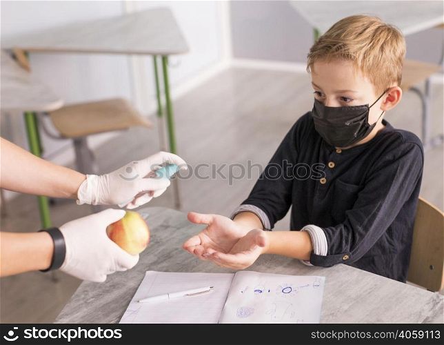 kid disinfecting his hands before eating apple
