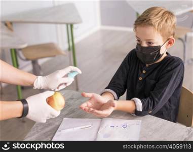 kid disinfecting his hands before eating apple