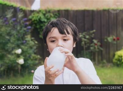 Kid drinking water, Thirsty boy holding a bottle of water, Child drinking water while playing in the garden, World Children day, World Environment Day