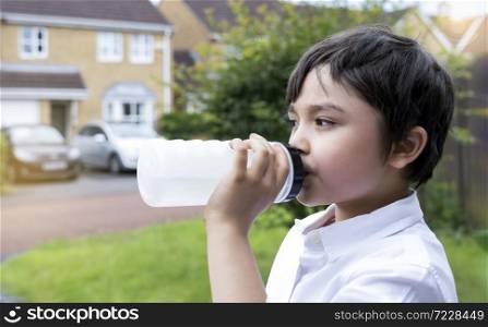 Kid drinking water, Thirsty boy holding a bottle of water, Healthy Child with fresh face after drinking water while walking, World Water day, Children health care