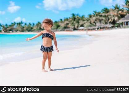 Kid fun. Little girl playing and splashing in waves on tropical beach. Cute little girl at beach during caribbean vacation