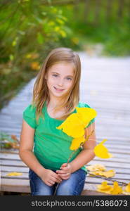 Kid girl in autumn wood deck with yellow leaves relaxed outdoor