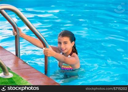 Kid girl in swimming pool at summer vacation posing looking camera