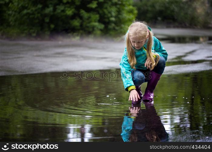 kid girl playing in a puddle on a rainy day