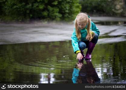 kid girl playing in a puddle on a rainy day