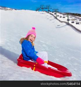 Kid girl playing sled in snow with winter wool pink hat