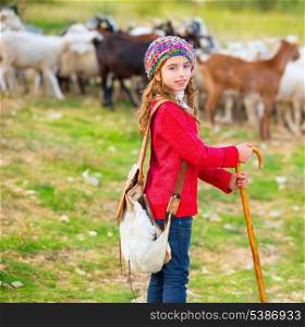 Kid girl shepherdess happy with flock of sheep and wooden stick in Spain