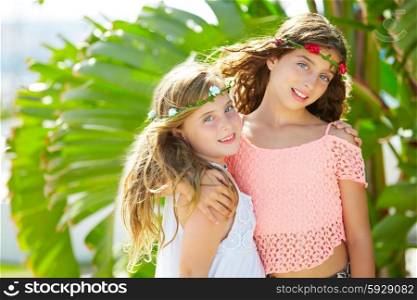 kid girl sisters hug at banana tree leaves in bright day light in Mediterranean