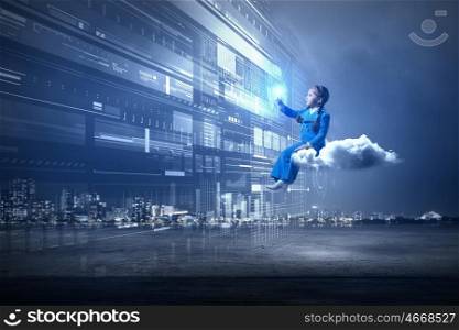 Kid girl using modern technologies. Little girl sitting on cloud and touching virtual panel with finger