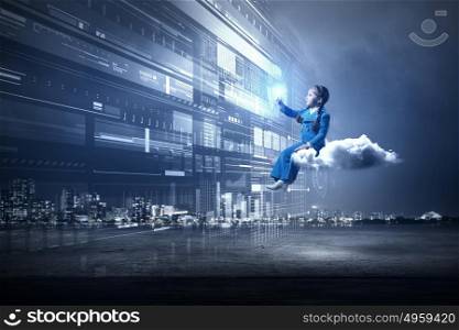 Kid girl using modern technologies. Little girl sitting on cloud and touching virtual panel with finger