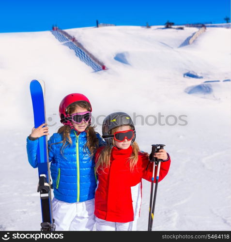 Kid girls sister in winter snow with ski equipment helmet goggles poles