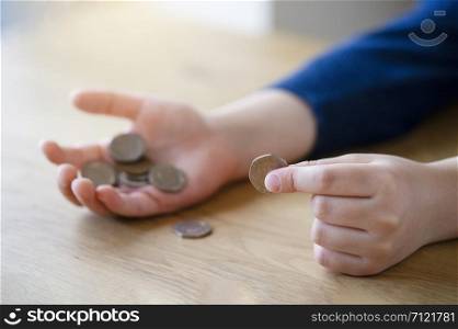 Kid hand holding pound coins on wooden table, Kid learning counting and how different about money coins, Children learning about financial responsibility or planning savings concept.
