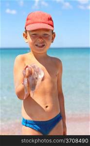 Kid is holding a jellyfish on the sea beach