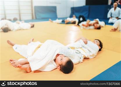 Kid judo, fight training, martial art, self-defense. Little boys in uniform in sport gym, young fighters