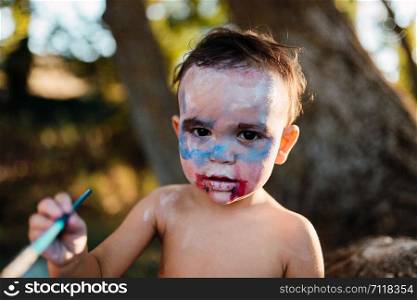 Kid painting himself of dracula to halloween on the forest