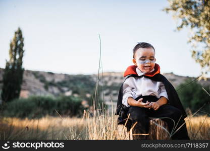 Kid painting himself of dracula to halloween on the forest