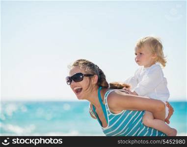 Kid piggybacking mother on beach