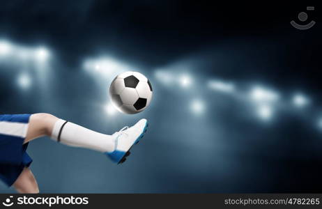 Kid play soccer on stadium. Leg of kid boy in blue uniform on soccer stadium kicking ball