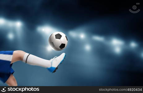 Kid play soccer on stadium. Leg of kid boy in blue uniform on soccer stadium kicking ball