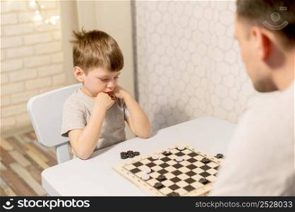 kid playing chess with father
