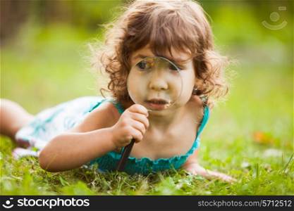 Kid plays with magnifying glass in the garden