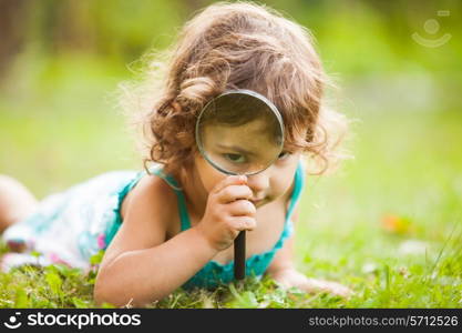 Kid plays with magnifying glass in the garden