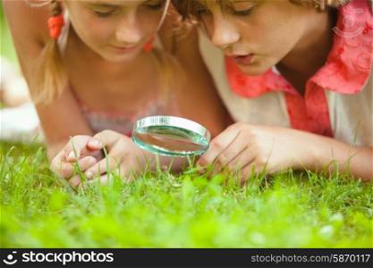Kid plays with magnifying glass in the garden. Kid with magnifying glass