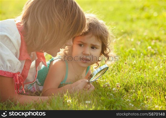 Kid plays with magnifying glass in the garden. Kid with magnifying glass