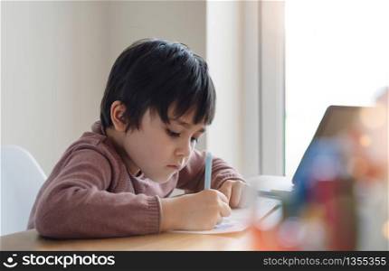 Kid self isolation using tablet for his homework,Child doing using digital tablet searching information on internet during covid lock down, Home schooling,Social Distance, E-learning online education