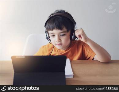Kid self isolation using tablet for his homework,Child doing using digital tablet searching information on internet during covid lock down, Home schooling,Social Distance, E-learning online education